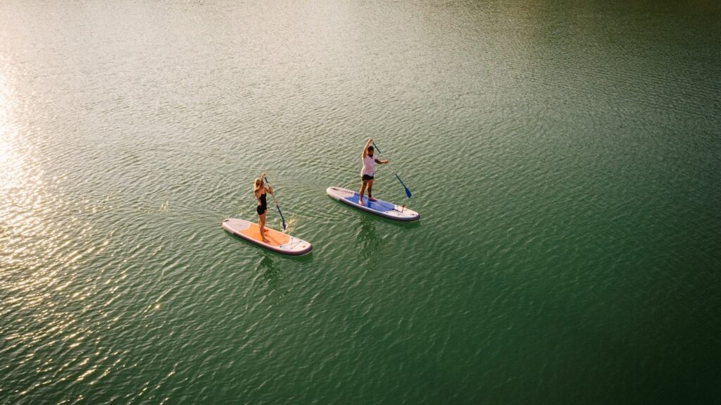 two people standing up on paddle boards on the water with their paddles in the water